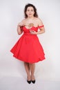 Plump woman in a red pinup dress. chubby fashionable girl standing on white background in Studio Royalty Free Stock Photo