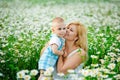 A plump woman and a small one-year-old boy in a field of daisies. A mother has fun with her son in a blooming field of chamomile
