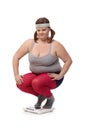 Plump woman squatting on scale disappointed