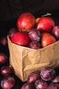 Plums and apples in the craft package on a black background