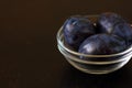 Plums blue prune in a glass bowl on a dark countertop
