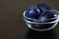 Plums blue prune in a glass bowl on a dark countertop