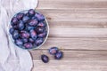 Plums in a bowl and napkin on wooden background. Top view. Royalty Free Stock Photo