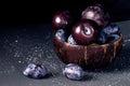 Plums in a coconut bowl on a dark background