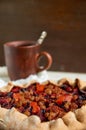 Plums pie with dried apricots close up. On blurred background a cup of tea on brown wooden background Royalty Free Stock Photo