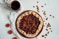 Plums pie with dried apricots on dark plate decorated with brown raisins and a cup of tea on light table with white cloth Royalty Free Stock Photo