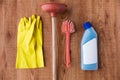 Plunger with cleaning stuff on wooden background