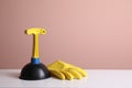 Plunger and rubber glove on white table against pink background. Space for text