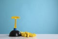 Plunger and rubber glove on white table against turquoise background. Space for text