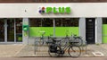 Plus logo sign. Plus is a supermarket groceries store with bikes parked in front of the shop.