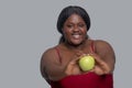 Plus size african american young woman in red showing an apple and smiling Royalty Free Stock Photo