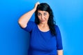 Plus size brunette woman wearing casual blue shirt confuse and wonder about question Royalty Free Stock Photo