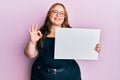 Plus size caucasian young woman holding blank empty banner doing ok sign with fingers, smiling friendly gesturing excellent symbol Royalty Free Stock Photo