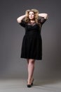 Plus size fashion model in black dress, fat woman on gray background Royalty Free Stock Photo