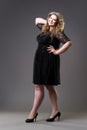 Plus size fashion model in black dress, fat woman on gray background Royalty Free Stock Photo