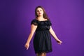 Plus size fashion model in black dress, fat woman on purple background Royalty Free Stock Photo