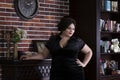 Plus size fashion model in black evening dress, fat woman on luxury interior, overweight female body Royalty Free Stock Photo