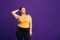 Plus size fashion model in casual clothes, fat woman on purple background