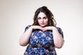 Plus size fashion model in floral blouse, fat woman on beige background