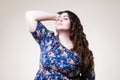 Plus size fashion model in floral blouse, fat woman on beige background
