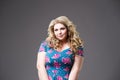 Plus size fashion model in floral dress, fat woman on gray background