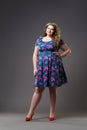 Plus size fashion model in floral dress, fat woman on gray background