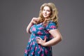 Plus size fashion model in floral dress, fat woman on gray background
