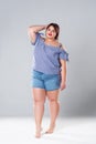 Plus size fashion model in jean shorts, fat woman on gray background Royalty Free Stock Photo