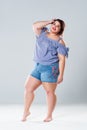 Plus size fashion model in jean shorts, fat woman on gray background Royalty Free Stock Photo