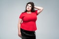 Plus size fashion model in red blouse and black skirt, fat woman on gray background, body positive concept Royalty Free Stock Photo