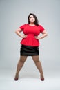 Plus size fashion model in red blouse and black skirt, fat woman on gray background, body positive concept Royalty Free Stock Photo