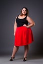 Plus size fashion model in red skirt, fat woman on gray background, overweight female body