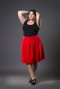 Plus size fashion model in red skirt, fat woman on gray background, overweight female body Royalty Free Stock Photo