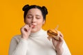Plus Size Girl Eating Cheeseburger Sandwich And Licking Fingers With Appetite