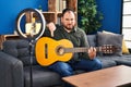 Plus size hispanic man with beard playing classic guitar at music studio recording himself with angry face, negative sign showing Royalty Free Stock Photo