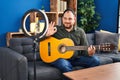 Plus size hispanic man with beard playing classic guitar at music studio recording himself doing ok sign with fingers, smiling Royalty Free Stock Photo