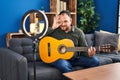 Plus size hispanic man with beard playing classic guitar at music studio recording himself smiling happy doing ok sign with hand Royalty Free Stock Photo