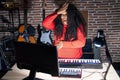 Plus size hispanic woman playing piano at music studio surprised with hand on head for mistake, remember error