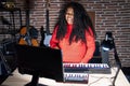 Plus size hispanic woman playing piano at music studio winking looking at the camera with sexy expression, cheerful and happy face