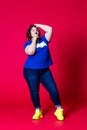 Plus size model in casual clothes, fat woman in blue jeans and t-shirt on red background