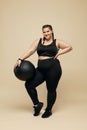 Plus Size Model. Fat Woman In Black Sportswear Full-Length Portrait. Smiling Brunette Holding Fitness Ball.