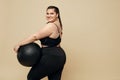 Plus Size Model. Full-Figured Woman In Black Sportswear Portrait. Brunette Holding Fitness Ball.