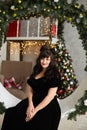 Plus size model girl in the interior decorated for New year. Fashionable plump brunette woman in black evening dress