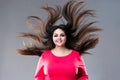 Plus size model with long hair blowing in the wind, brunette fat woman on gray background, body positive concept Royalty Free Stock Photo