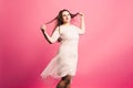 Plus size model with long hair blowing in the wind, fat woman on pink background Royalty Free Stock Photo