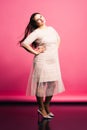 Plus size model with long hair blowing in the wind, fat woman on pink background Royalty Free Stock Photo