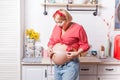 Plus size. Pleasant surprised pregnant woman holding measure type and using it on her belly while expressing wonder