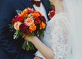 Plus size wedding couple is standing and hugging outside. Curvy bride is holding beautiful colorful bouquet with orange, red and Royalty Free Stock Photo