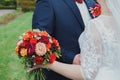 Plus size wedding couple is standing and hugging outside. Curvy bride is holding beautiful colorful bouquet with orange, red and Royalty Free Stock Photo