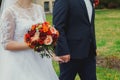 Plus size wedding couple is walking outside. Curvy bride is holding beautiful colorful bouquet with orange, red and pink peonies Royalty Free Stock Photo